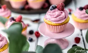 Ein köstliches Cupcake-Rezept mit rosa Frosting, garniert mit Blaubeeren und Himbeeren. Perfekt für süße Momente.
