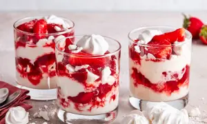 Drei Gläser mit Eton Mess: geschichtete Erdbeeren, Sahne und zerbrochene Baiser-Stücke. Ein süßer Genuss!