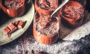 Schokoladenmousse in Gläsern, bestreut mit Schokostreuseln. Ein Löffel nimmt eine Portion auf. Perfekt für ein rezept mousse au chocolat ohne ei.