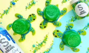 Drei grüne Wackelpudding-Schildkröten mit Streuseln und einem Drip-Fläschchen. Lustige Wackelpudding-Ideen für den Sommer.
