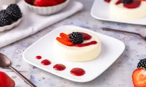 Cremige Panna Cotta, einfach im Thermomix zubereitet, garniert mit frischen Beeren und Erdbeersauce.