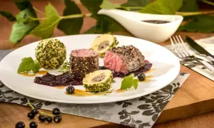 Edles Fleisch mit Kräuterkugeln und einer dunklen Sauce, inspiriert von schwarzen johannisbeere rezepten.