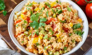Bunter Couscous-Salat mit Tomaten, Paprika und frischer Petersilie, garniert mit einem Petersilienblatt.