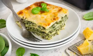 Ein Stück Spinatlasagne mit Käse überbacken, garniert mit Basilikum. Ein köstliches spinatlasagne rezept.