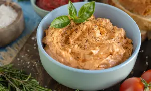Cremige italienische Tomatenbutter, garniert mit Basilikum und Pfeffer, bereit zum Genuss.