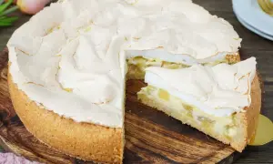 Ein saftiger Rhabarberkuchen mit Baiserhaube, ein Stück wurde bereits entnommen.