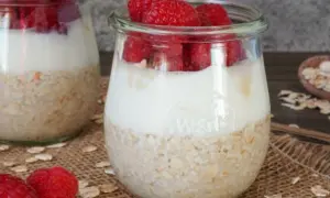 Zwei Gläser mit overnight oats mit joghurt und frischen Himbeeren. Ein gesunder Start in den Tag.