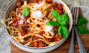 Eine Schüssel mit Linguine und einer herzhaften, **schnellen Bolognese** Soße, garniert mit frischem Basilikum und Parmesan.