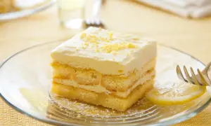Ein Stück Limoncello Tiramisu auf einem Teller, garniert mit Zitronenschale. Ein Hauch von Sommer auf jedem Löffel.