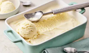 Ein Behälter mit cremigem Vanilleeis, perfekt zum vanilleeis selber machen. Ein Löffel liegt bereit, um die erste Kugel zu entnehmen.