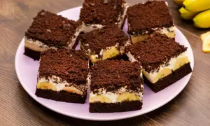 Saftiger Maulwurfkuchen vom Blech mit Bananen und Schokostreuseln auf einem rosa Teller.