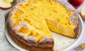 Ein saftiger Apfelkuchen mit Quark, bestäubt mit Puderzucker. Ein Stück fehlt bereits, bereit zum Genuss.