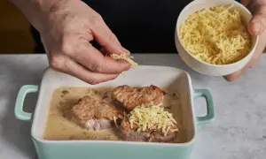 Zarte schweine medaillons in cremiger Sauce werden mit geriebenem Käse bestreut.