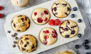 Leckeres mini muffins rezept: Schoko-, Himbeer- und Blaubeermuffins in einer Muffinform, garniert mit frischen Beeren und Puderzucker.