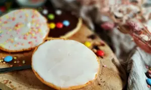 Bunte Kekse mit Zuckerguss und Schokoladenglasur, inspiriert von einem amerikanischen Rezept, liegen auf einem Holzbrett.