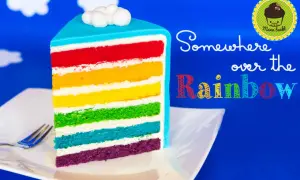 Ein Stück regenbogen kuchen mit bunten Schichten und Wolken-Topping.