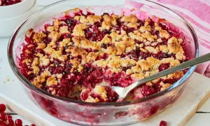 Ein leckerer Johannisbeer Crumble in einer Glasform, mit knuspriger Streuselhaube und saftiger roter Füllung.