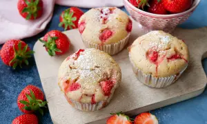 Saftige Erdbeermuffins, perfekt für jeden Kindergeburtstag, mit Puderzucker bestäubt und frischen Erdbeeren garniert.