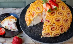 Eine köstliche Erdbeer-Charlotte, bedeckt mit Biskuitrollen, die mit Erdbeermarmelade gefüllt sind. Ein Stück wurde bereits entnommen.