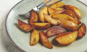 Goldbraune, knusprige Kartoffeln im Ofen auf einem Teller, bereit zum Genießen. Ein Gabel liegt daneben.