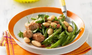 Bohnensalat rezept: Frischer Bohnensalat mit weißen Bohnen, grünen Bohnen, Thunfisch und Kräutern auf einem Teller mit orangem Rand.