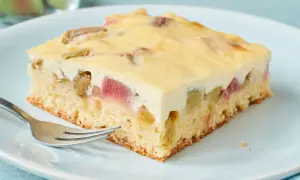 Ein Stück saftiger Rhabarber-Blechkuchen mit cremiger Füllung und einem lockeren Boden, bereit zum Genießen.