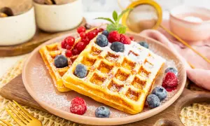 Goldene protein waffeln rezept mit frischen Beeren und Puderzucker bestäubt. Ein köstlicher Start in den Tag!