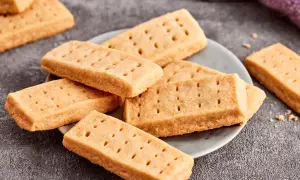 Goldbraune Shortbread-Kekse, perfekt für ein einfaches Shortbread Rezept. Sie liegen auf einem Teller und daneben ein lila Tuch.