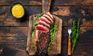 Perfekt gegrillte Ente auf Holzbrett, mit Rucola und Sauce. Die Kerntemperatur der Ente messen ist wichtig für den perfekten Garpunkt.
