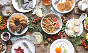 Leckere Brunch-Ideen: Marmorkuchen, Pancakes, Müsli, Obst und kleine Törtchen auf rustikalem Holztisch.