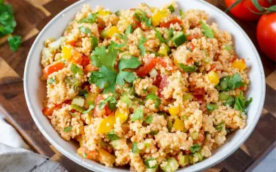 Bunter Couscous-Salat mit Tomaten, Paprika und frischer Petersilie, garniert mit einem Petersilienblatt.
