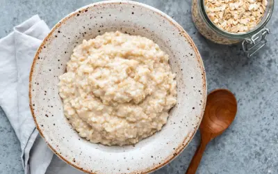 Cremiger Haferbrei in einer Schale, daneben ein Glas Haferflocken. Ein einfaches Porridge Rezept für einen gesunden Start.