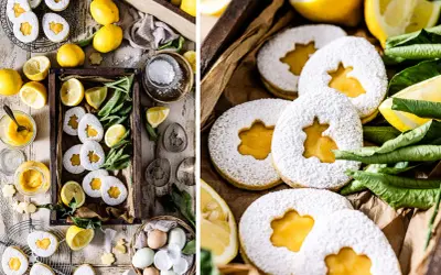 Osterkekse mit Zitrone und Puderzucker, gefüllt mit leckerer Zitronencreme. Frische Zitronen und grüne Blätter umgeben die süßen Leckereien.