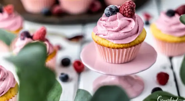 Ein köstliches Cupcake-Rezept mit rosa Frosting, garniert mit Blaubeeren und Himbeeren. Perfekt für süße Momente.