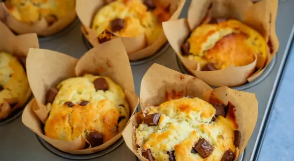 Frisch gebackene Schoko-Muffins im Papierförmchen, bereit für ein leckeres Muffins Rezept.