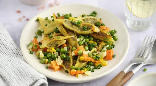 Gebratene Maultaschen mit Erbsen, Karotten und Mais, garniert mit Schnittlauch. Ein herzhaftes Gericht, das Lust auf mehr macht.