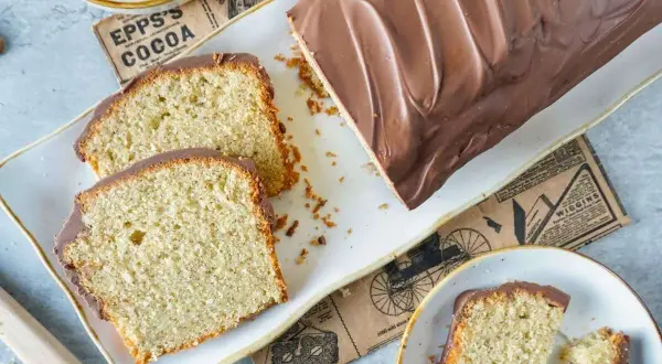 Saftiger Nusskuchen mit Schokoladenglasur, perfekt für Ihr nächstes nusskuchen rezept. Daneben liegen Walnüsse und ein Stück Kuchen.