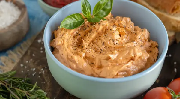 Cremige italienische Tomatenbutter, garniert mit Basilikum und Pfeffer, bereit zum Genuss.