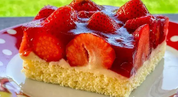 Ein Stück saftiger, **schneller Erdbeerkuchen vom Blech ohne Pudding**, belegt mit frischen Erdbeeren und glänzendem Tortenguss.