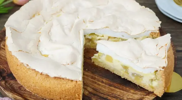 Ein saftiger Rhabarberkuchen mit Baiserhaube, ein Stück wurde bereits entnommen.