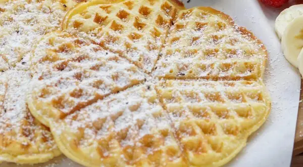 Zarte Buttermilch Waffeln, bestäubt mit Puderzucker, warten auf ein leckeres Frühstück.