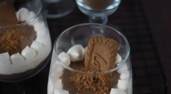 Cremiges Lotus Dessert im Glas, garniert mit Keksstückchen und einem ganzen Keks.