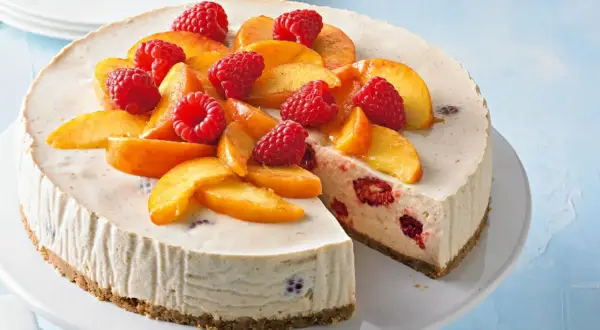 Cremiger Pfirsich Melba Kuchen mit frischen Himbeeren und Pfirsichspalten, ein Genuss für Augen und Gaumen.