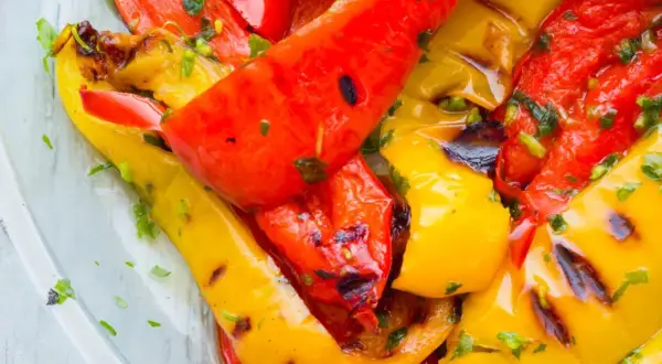 Leckeres Paprika grillen mit Kräutern. Rote und gelbe Paprikastreifen sind saftig und leicht angekohlt.