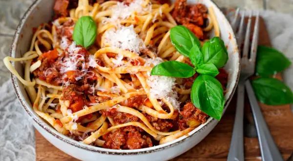 Eine Schüssel mit Linguine und einer herzhaften, **schnellen Bolognese** Soße, garniert mit frischem Basilikum und Parmesan.