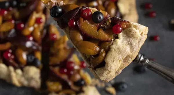 Ein Stück fruchtige Galette mit Pflaumen und Beeren, perfekt für ein einfaches Galette Rezept.
