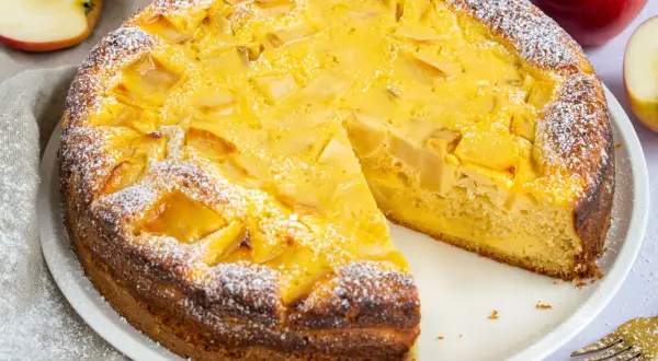 Ein saftiger Apfelkuchen mit Quark, bestäubt mit Puderzucker. Ein Stück fehlt bereits, bereit zum Genuss.