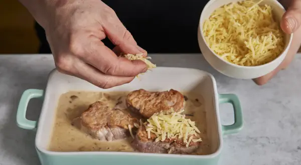 Zarte schweine medaillons in cremiger Sauce werden mit geriebenem Käse bestreut.