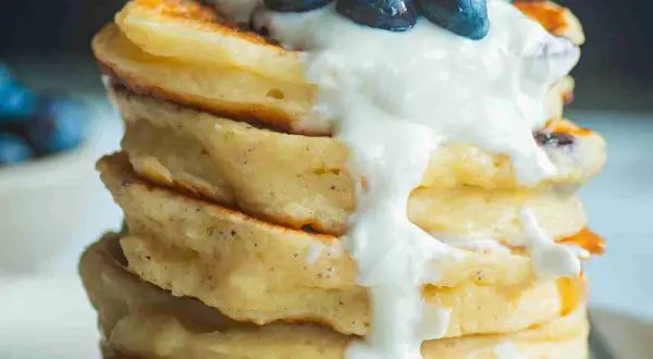Ein Stapel fluffiger Protein Pancakes mit Blaubeeren und Joghurt. Perfekt für ein gesundes Frühstück, inspiriert von einem protein pancakes rezept.
