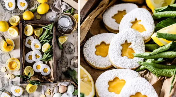 Osterkekse mit Zitrone und Puderzucker, gefüllt mit leckerer Zitronencreme. Frische Zitronen und grüne Blätter umgeben die süßen Leckereien.
